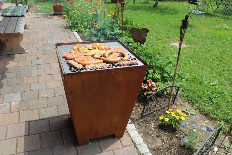 Cortenstahl Grill mit Grillgut im Garten